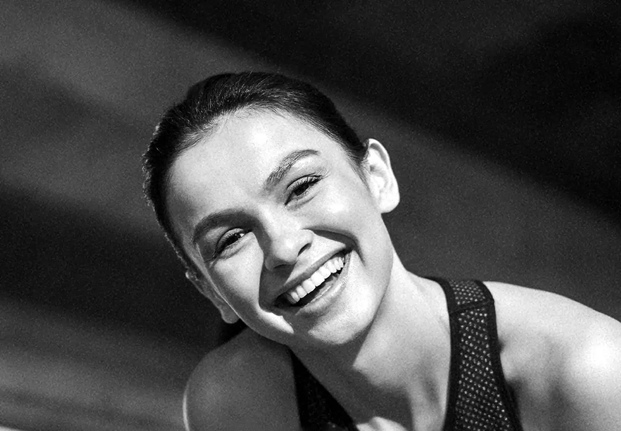 Mujer sonriendo con los ojos brillantes, en blanco y negro