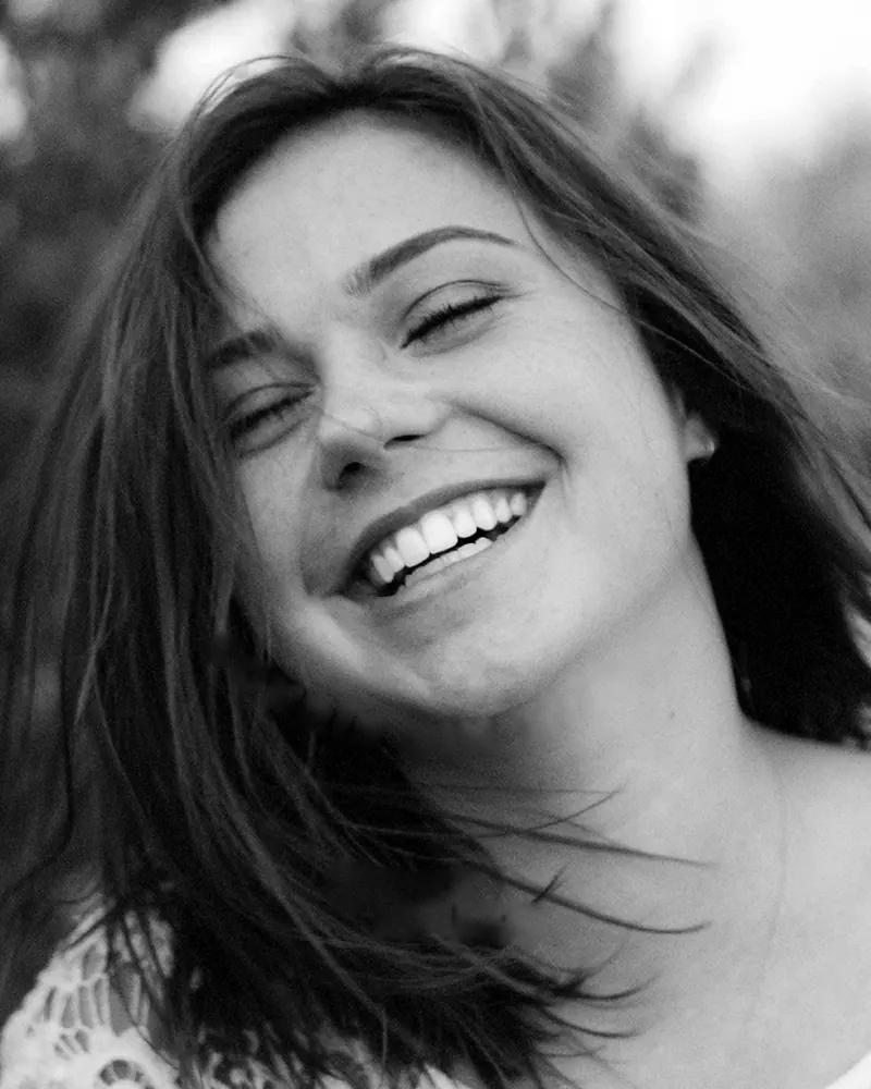 Mujer sonriendo con el cabello al viento, en blanco y negro
